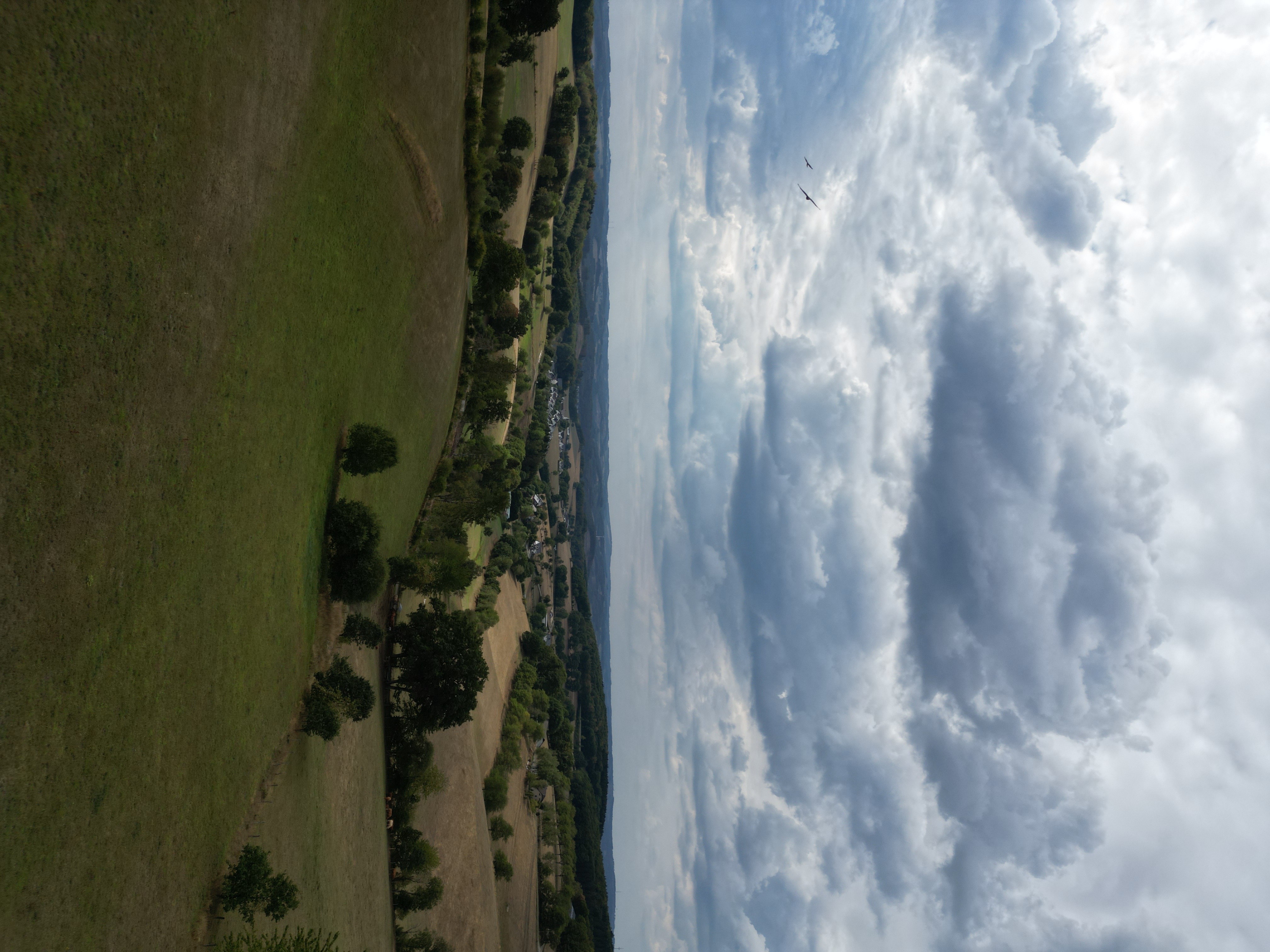 Luftaufnahme bei Olpe: hügelige Landschaft mit Feldern, Wäldern und einem Ort unter bewölktem Himmel